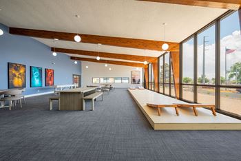 a large room with tables and benches and large windows